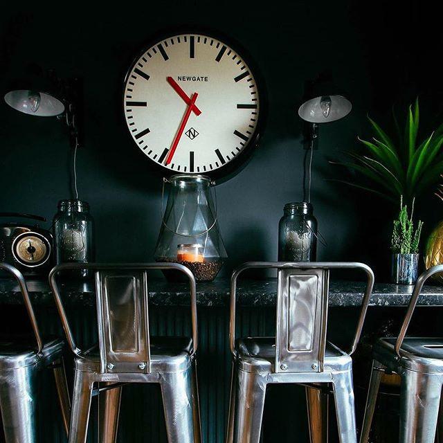 kuchnia w stylu eklektycznym, ciemne ściany, duży zegar ścienny, jasne krzesła kuchenne