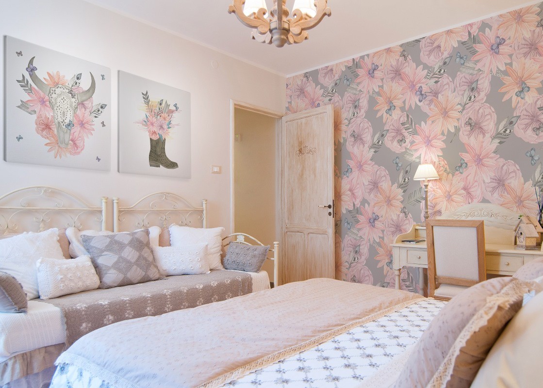 shabby chic aranżacja sypialni, kwiatowe motywy- tapeta, poduszki dekoracyjne z wzorem, obrazy, pastelowe odcienie